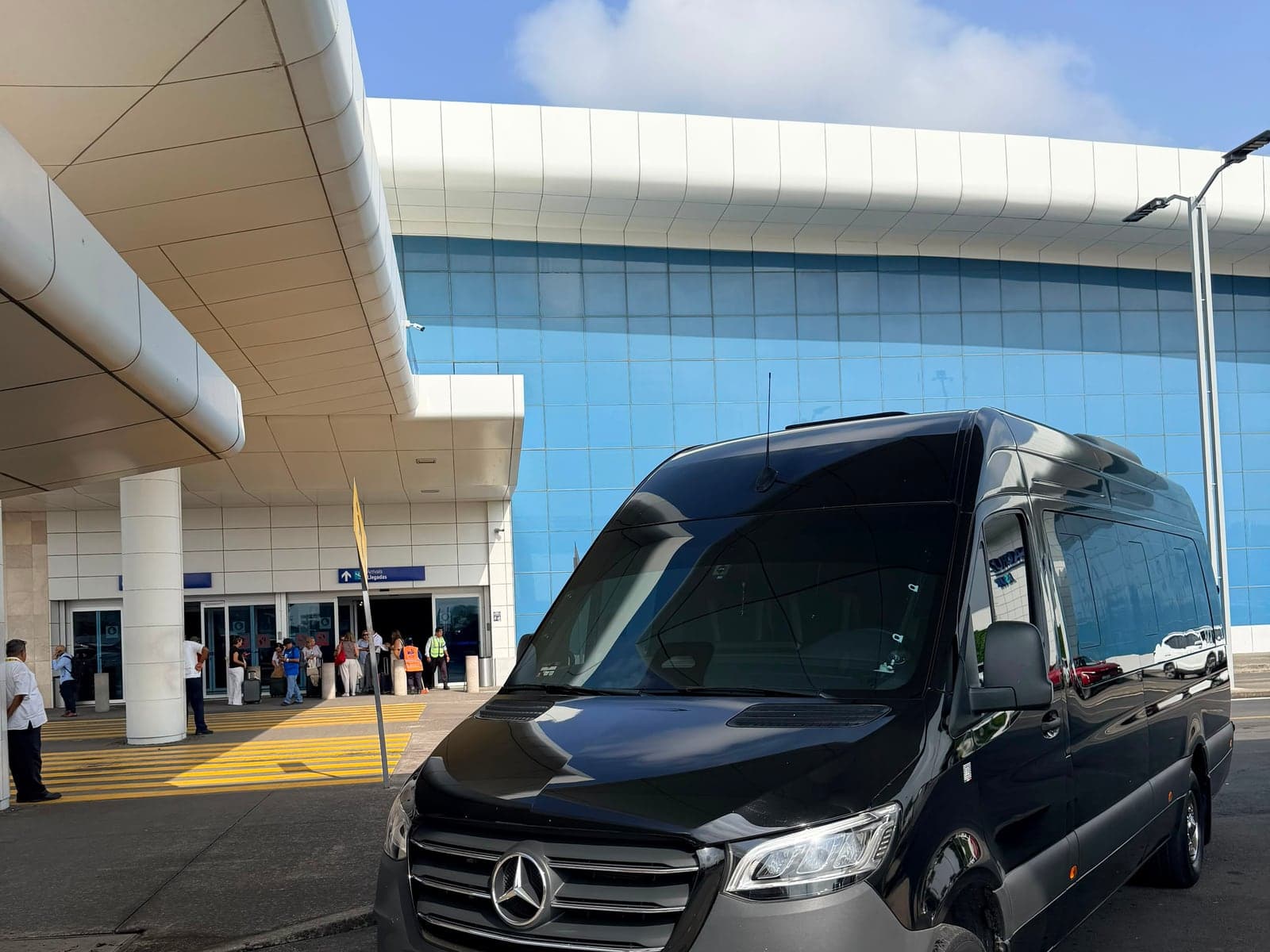 Mercedes-Benz Sprinter negra en posición frente a la terminal del aeropuerto